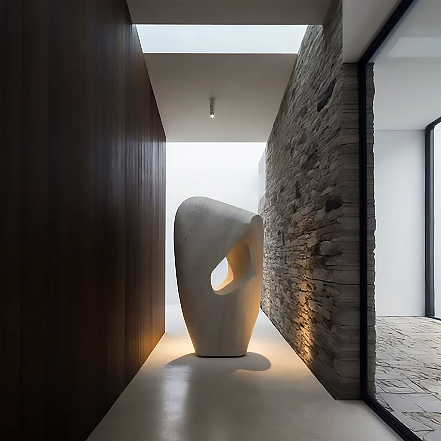 Hallway with organic stone sculpture, dark timber panelling and stacked stone wall